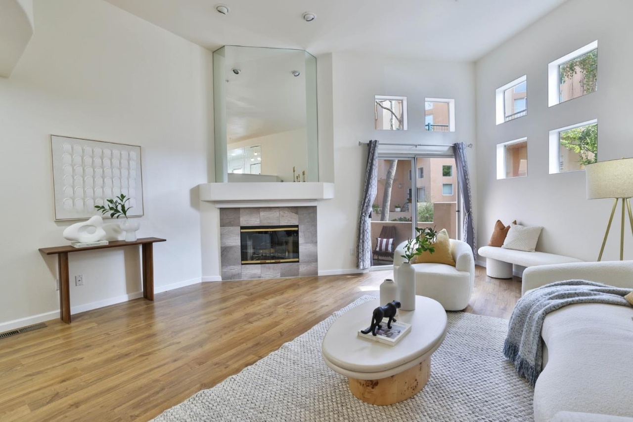 Living room seen from the far side, showing the tall mirrored chimney breast and the geometric window wall that gives the room its light